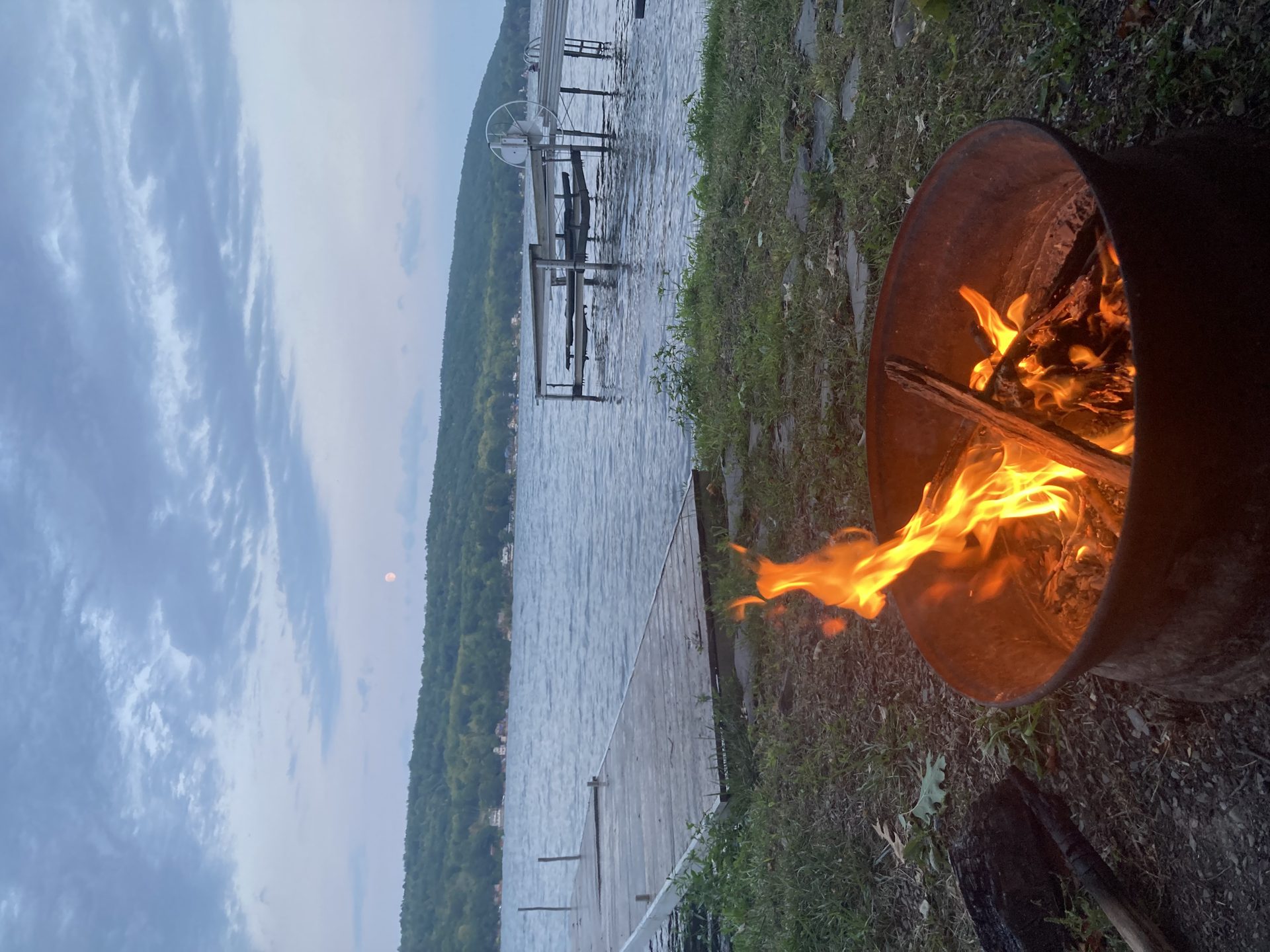 Fire pit burning at the lake's edge at dusk